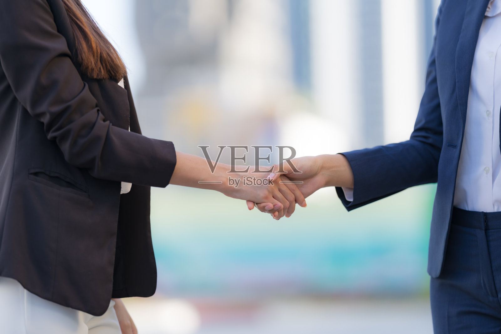 背景中有两位商界女性的握手照片摄影图片