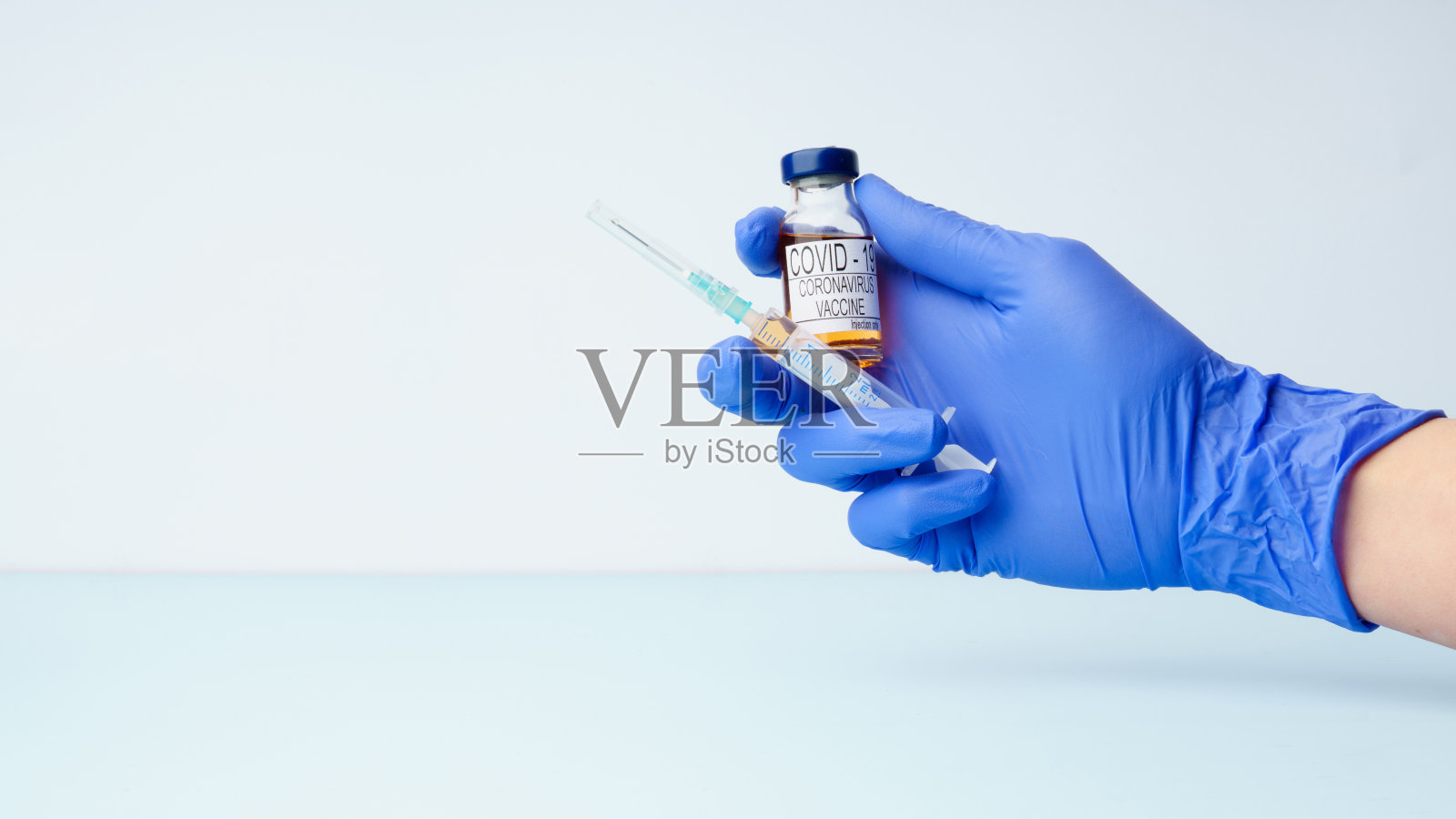 医生的手上戴着医用手套，上面拿着注射器和注射用的冠状病毒疫苗剂量瓶。照片摄影图片