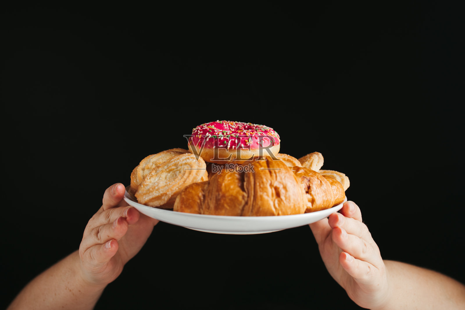 饮食。手拿着装着不健康糖果的盘子照片摄影图片