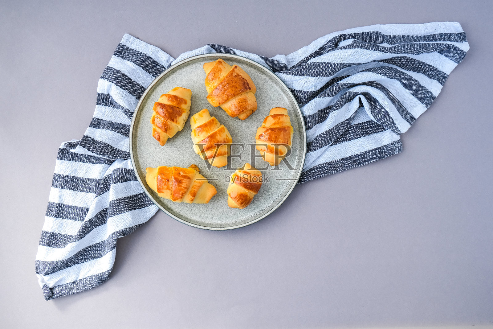 自制美味的羊角面包放在厨房毛巾上的灰色甜点盘里。美味的自制羊角面包蛋糕照片摄影图片