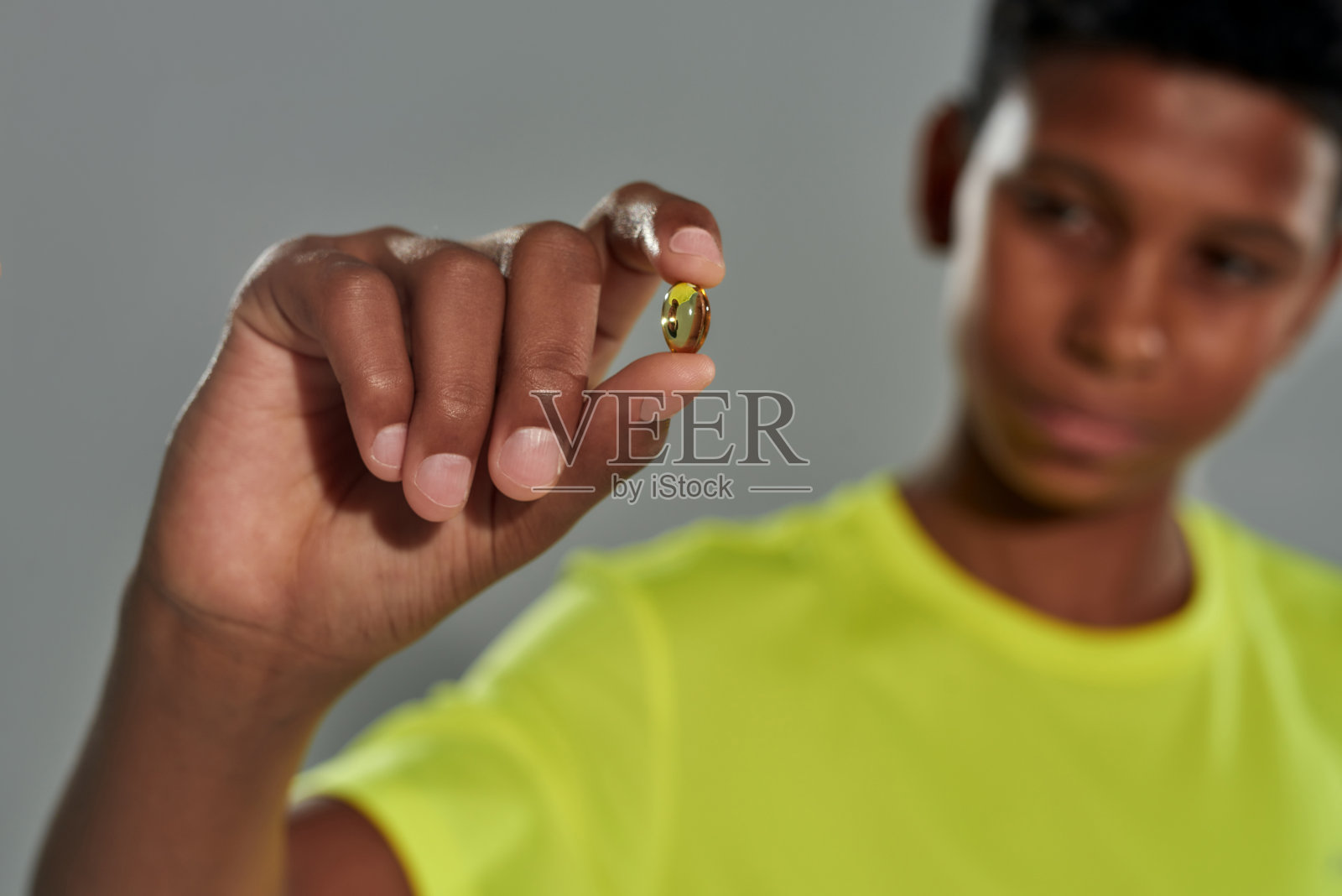 非洲少年拿着欧米茄3胶囊，有选择性地集中在手上照片摄影图片