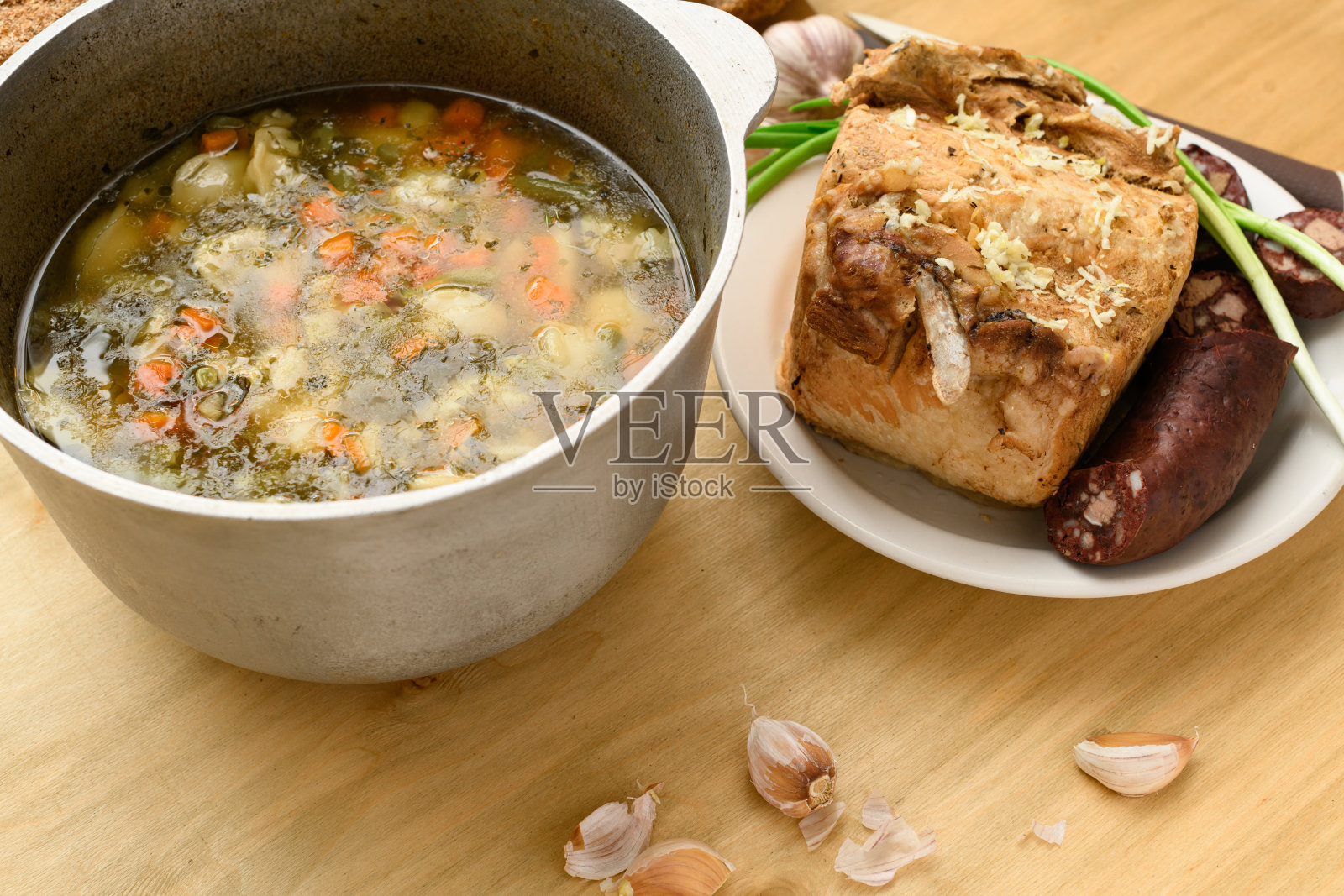 烤肉、汤和血肠放在盘子里，青葱和大蒜放在木头背景上，家常菜照片摄影图片