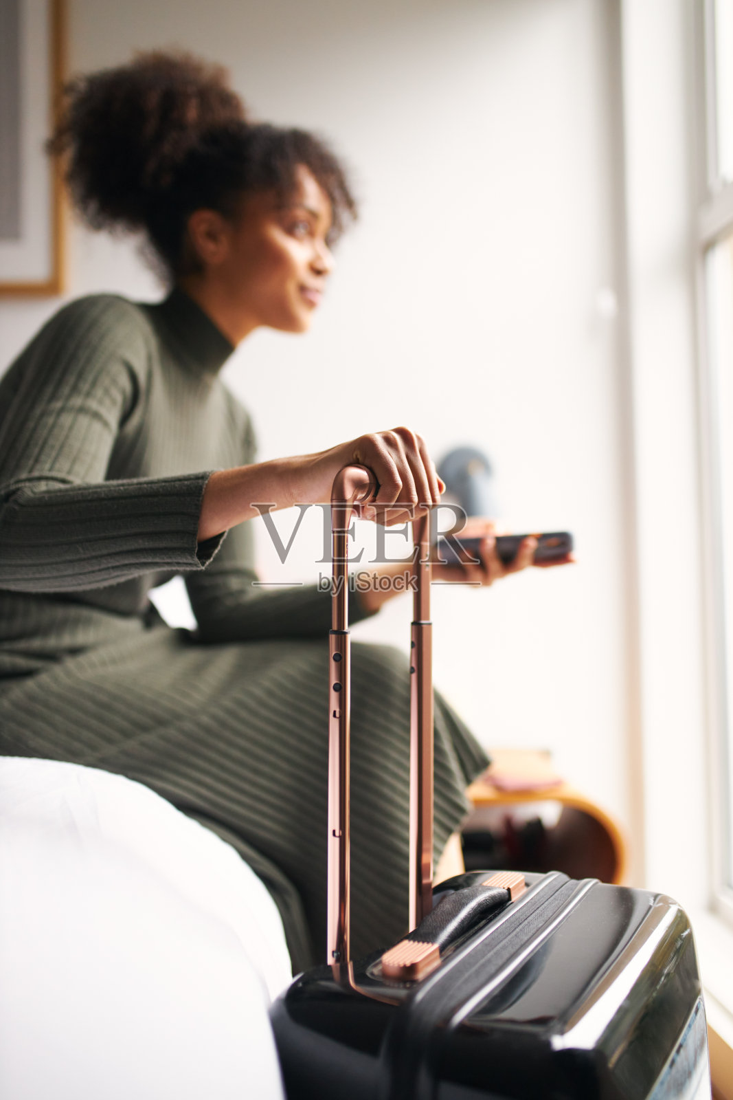 拿着旅行箱离开精品酒店的女士在手机App上预订出租车照片摄影图片