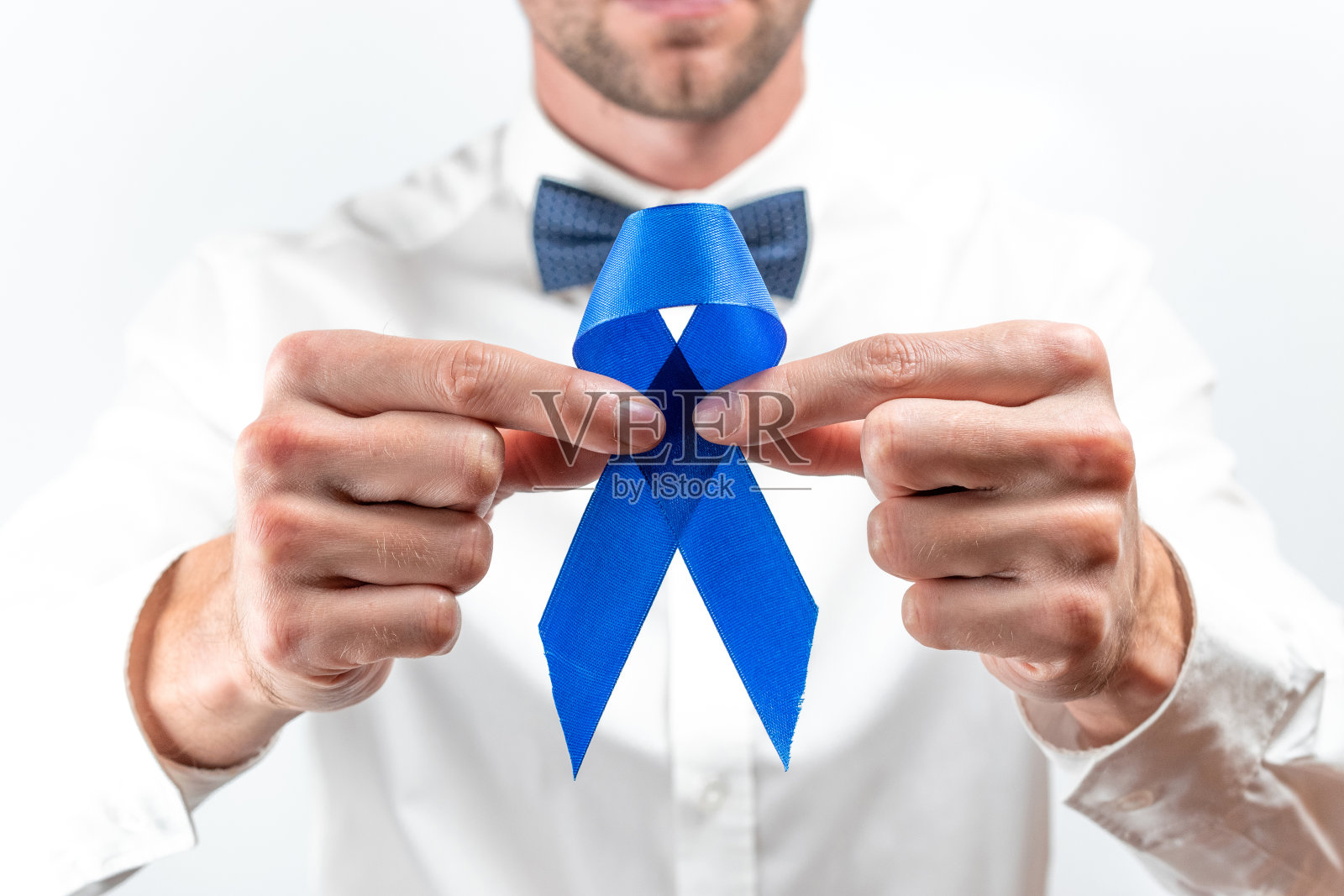 前列腺癌的治疗。11月提高前列腺对男性健康的认识。潮男在明亮的衬衫，青色领结与蓝色丝带在白色的背景。世界癌症日和世界糖尿病日的概念。照片摄影图片
