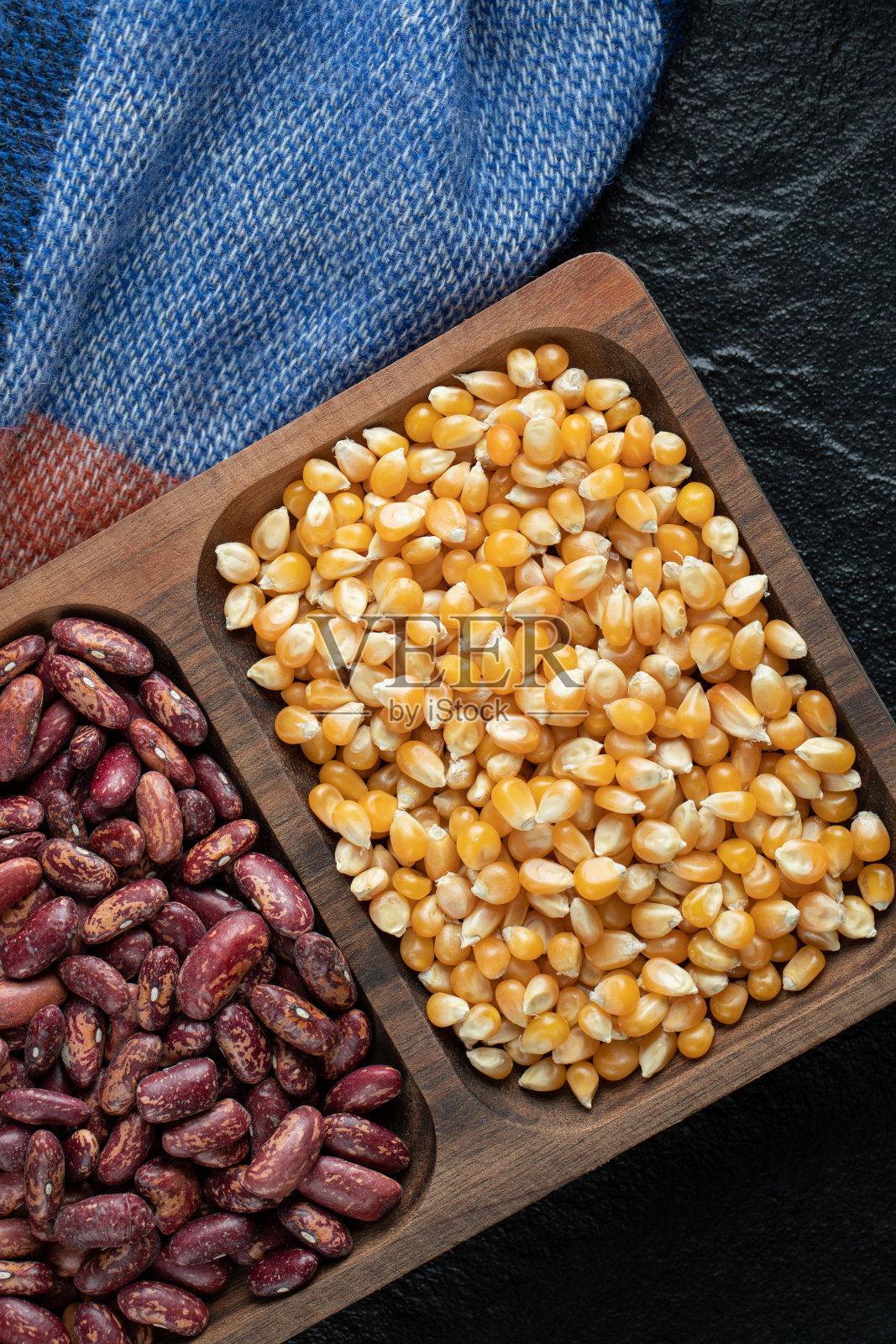 深色背景上放着生豆子和爆米花的木盘照片摄影图片