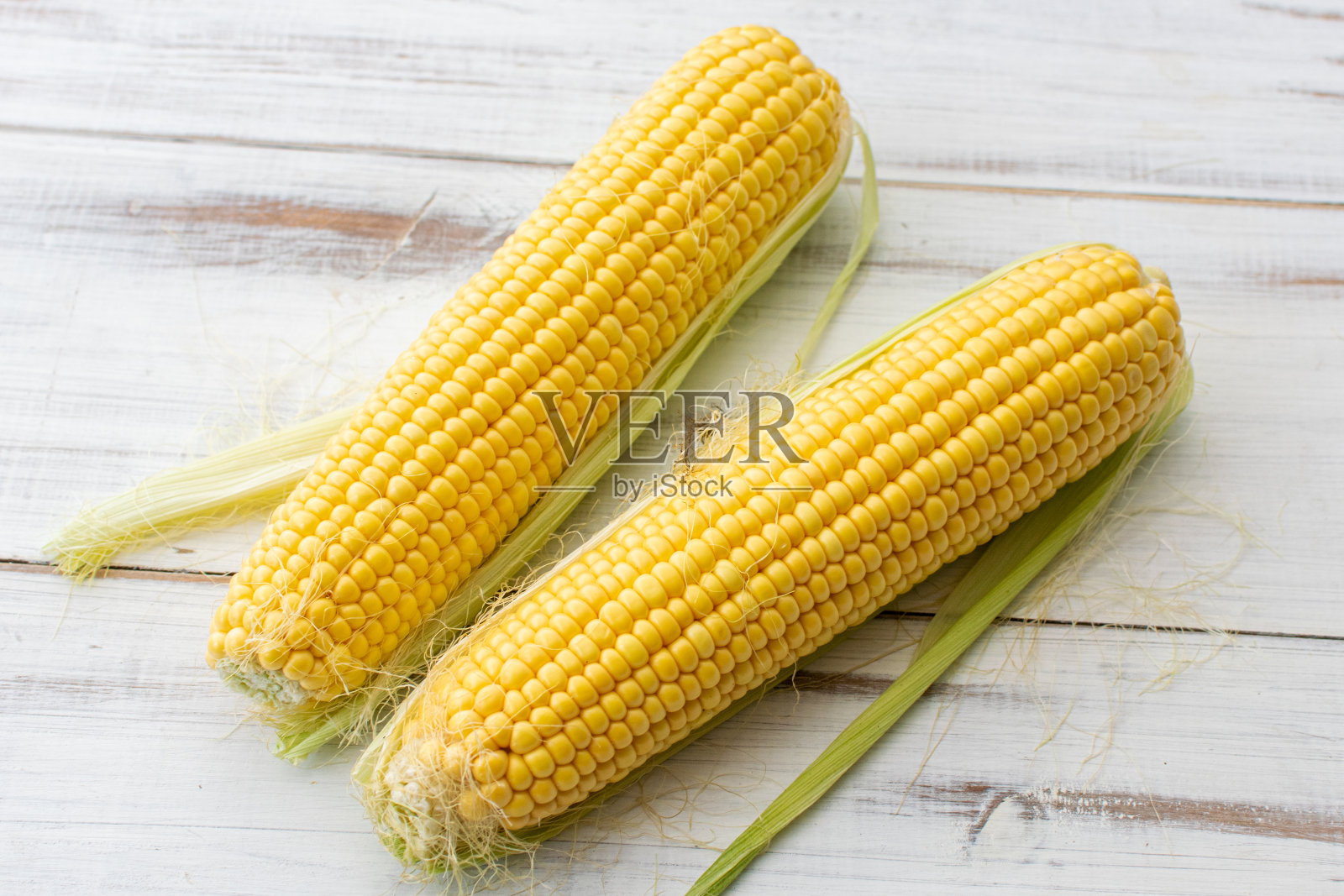 白色木质背景上的全玉米。素食。照片摄影图片