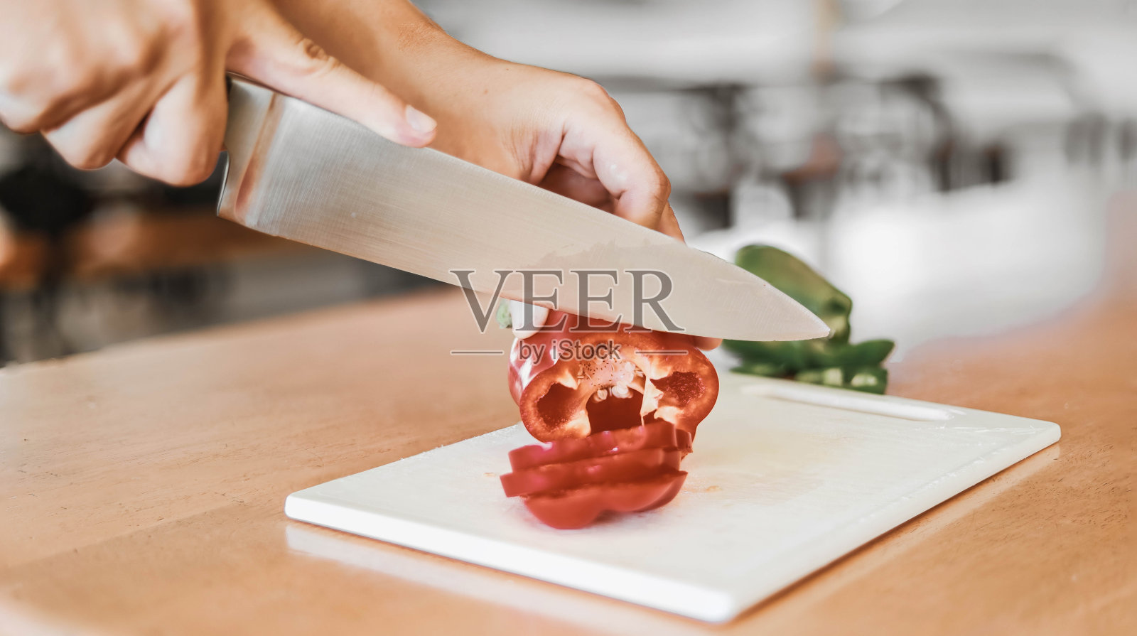 一个正在切红甜椒的男人。照片摄影图片