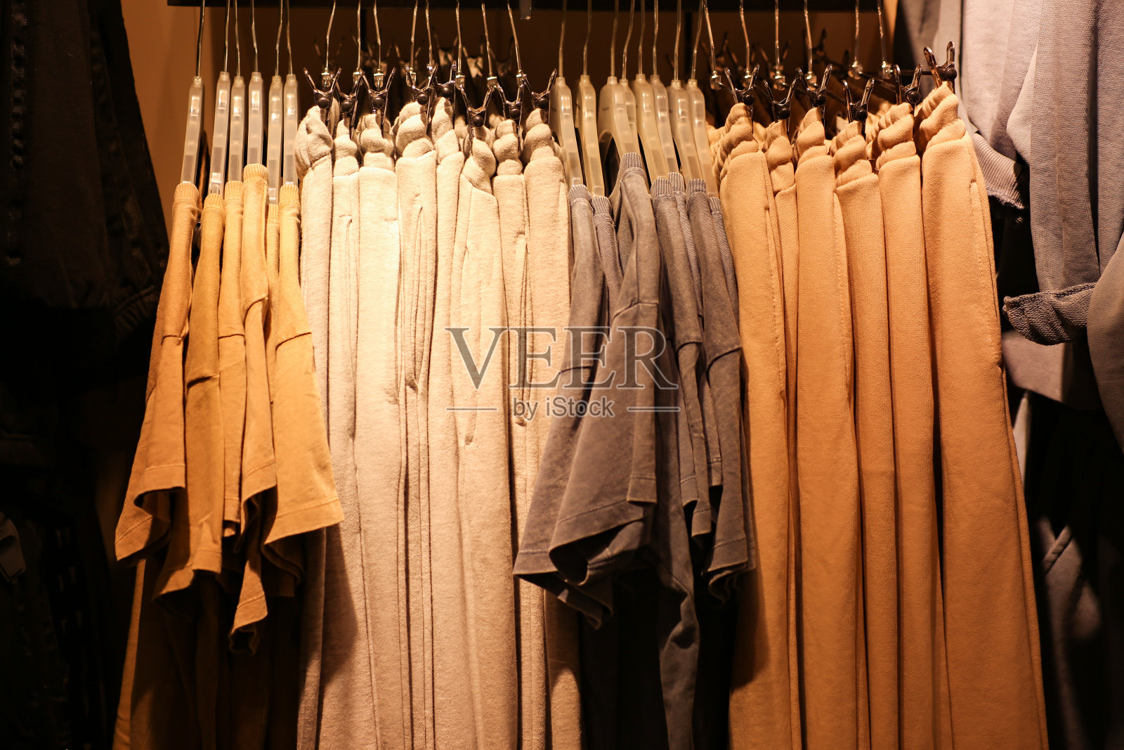 女性极简色彩柔和的衣服t恤和裤子挂在衣架上。照片摄影图片