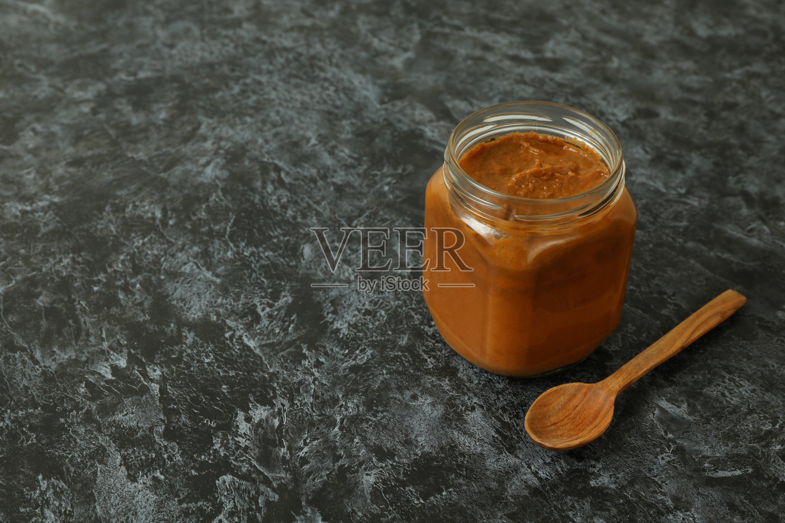 装有西葫芦鱼子酱和木勺，背景为黑色烟熏照片摄影图片