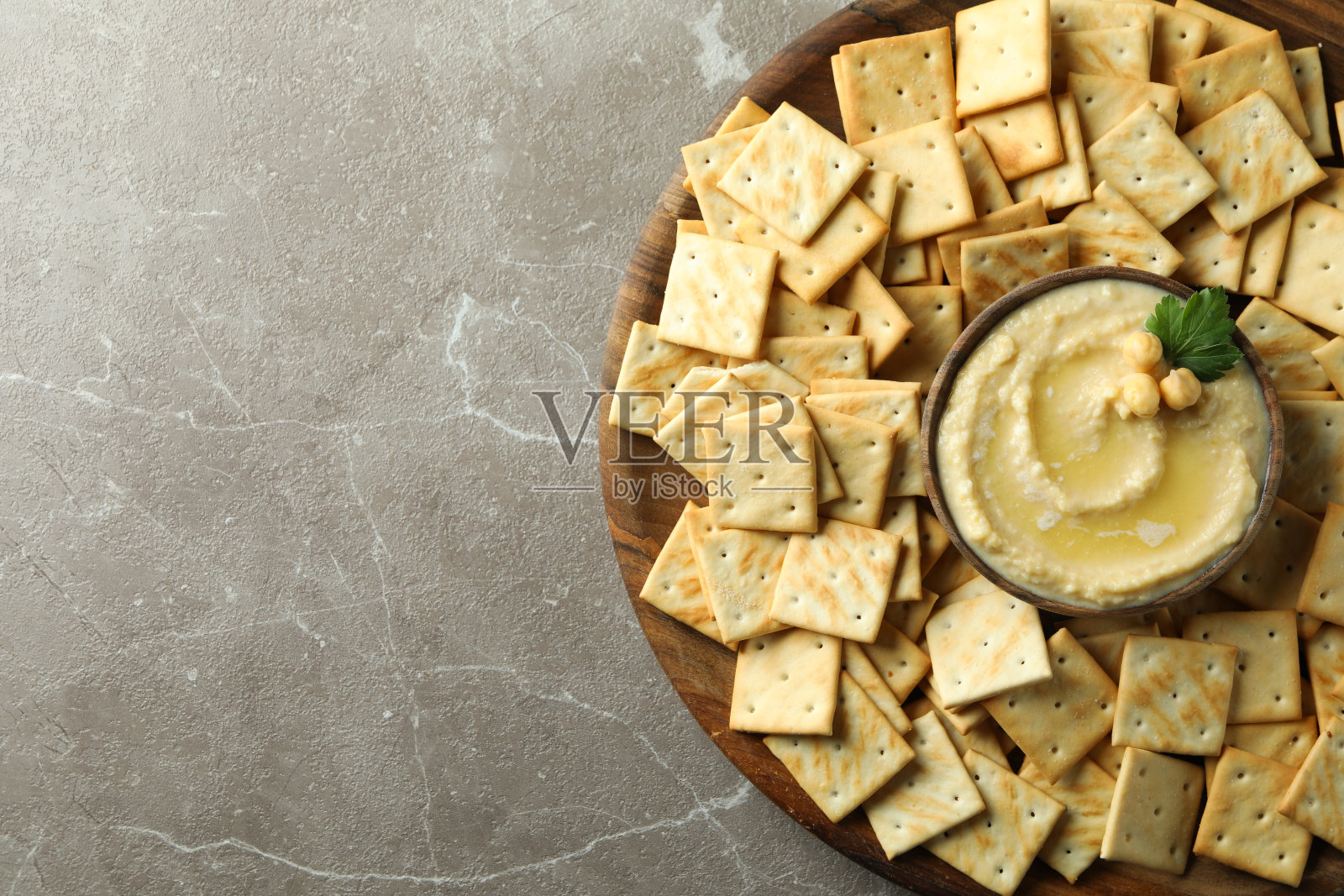 托盘上放着饼干和一碗鹰嘴豆泥，背景是灰色照片摄影图片