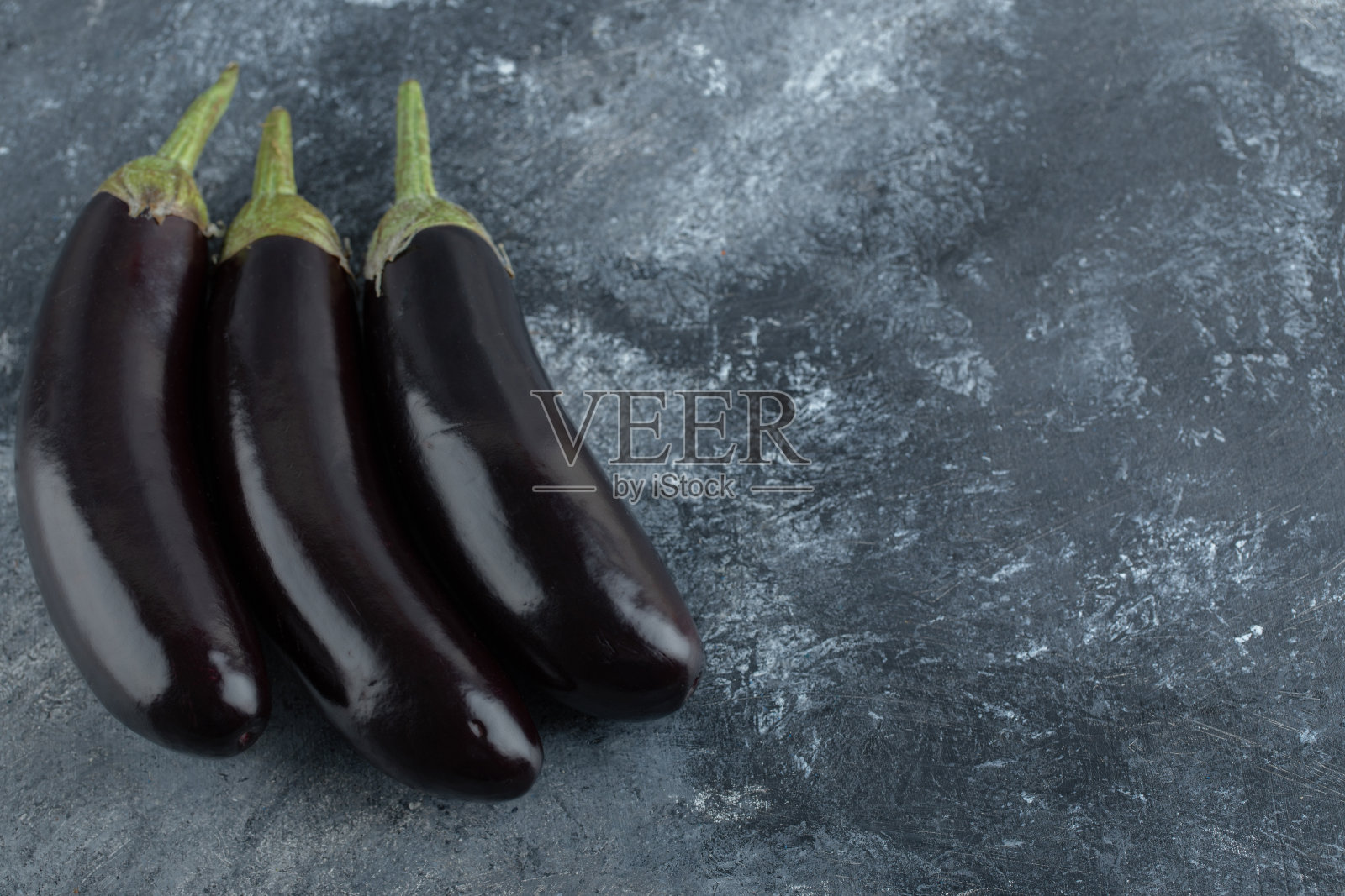 三个新鲜成熟的茄子在灰色的背景上照片摄影图片