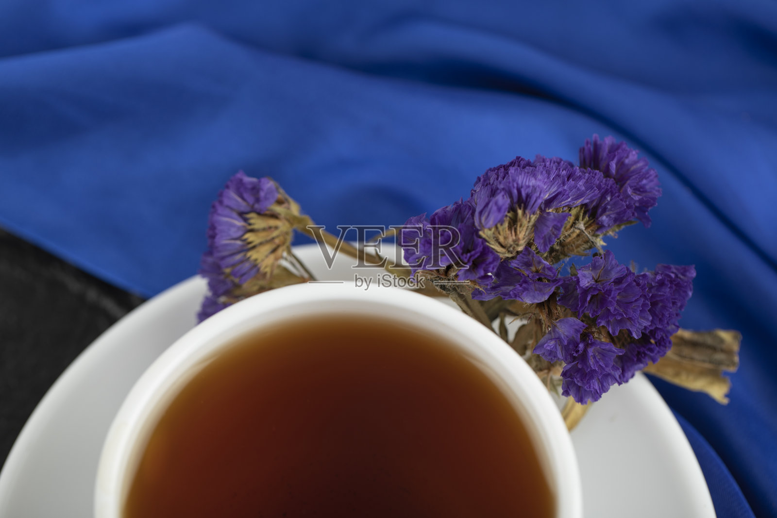 干紫色的花和一杯热茶在黑色的背景照片摄影图片