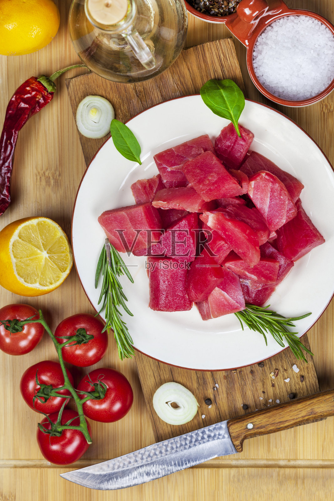 新鲜的金枪鱼片配上香料，蔬菜和香草放在盘子里。准备烤金枪鱼，俯视图照片摄影图片