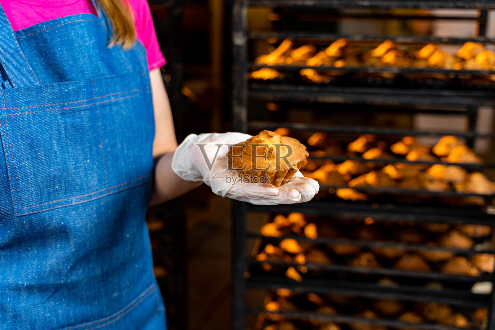 烘焙产品生产。年轻的女面包师手里拿着蛋糕在面包店。照片摄影图片