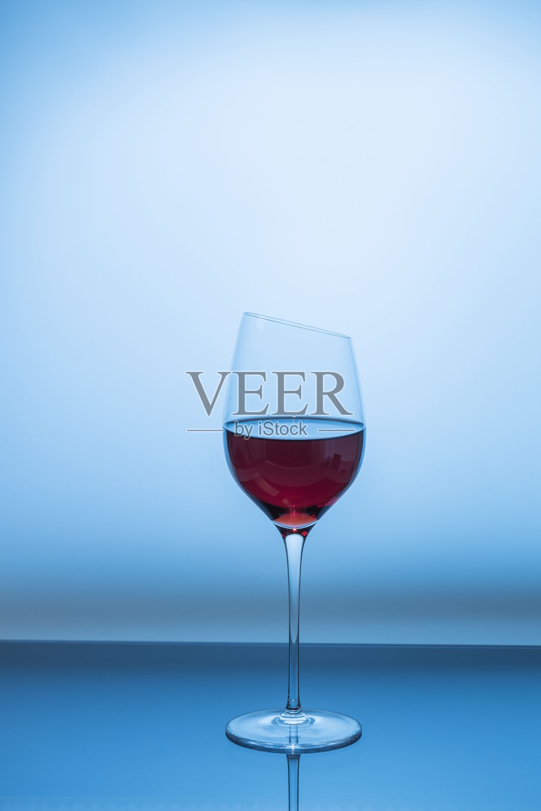 近距离观看红酒在玻璃上孤立的蓝色背景。照片摄影图片