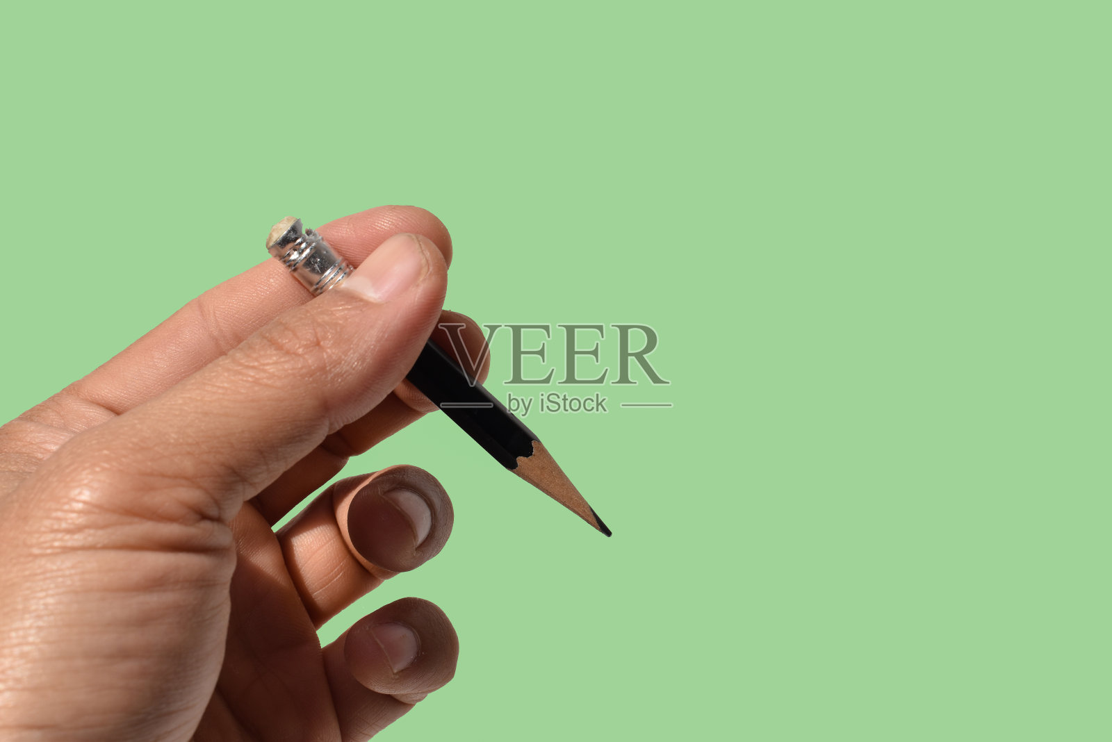 手握铅笔，绿色背景，留有拷贝空间照片摄影图片