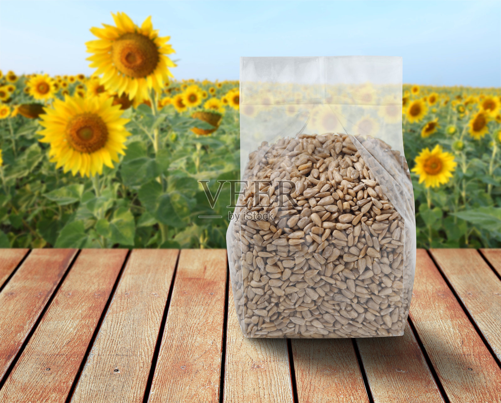 葵花籽装于塑料袋内，摆放在以葵花籽为背景的木桌上照片摄影图片
