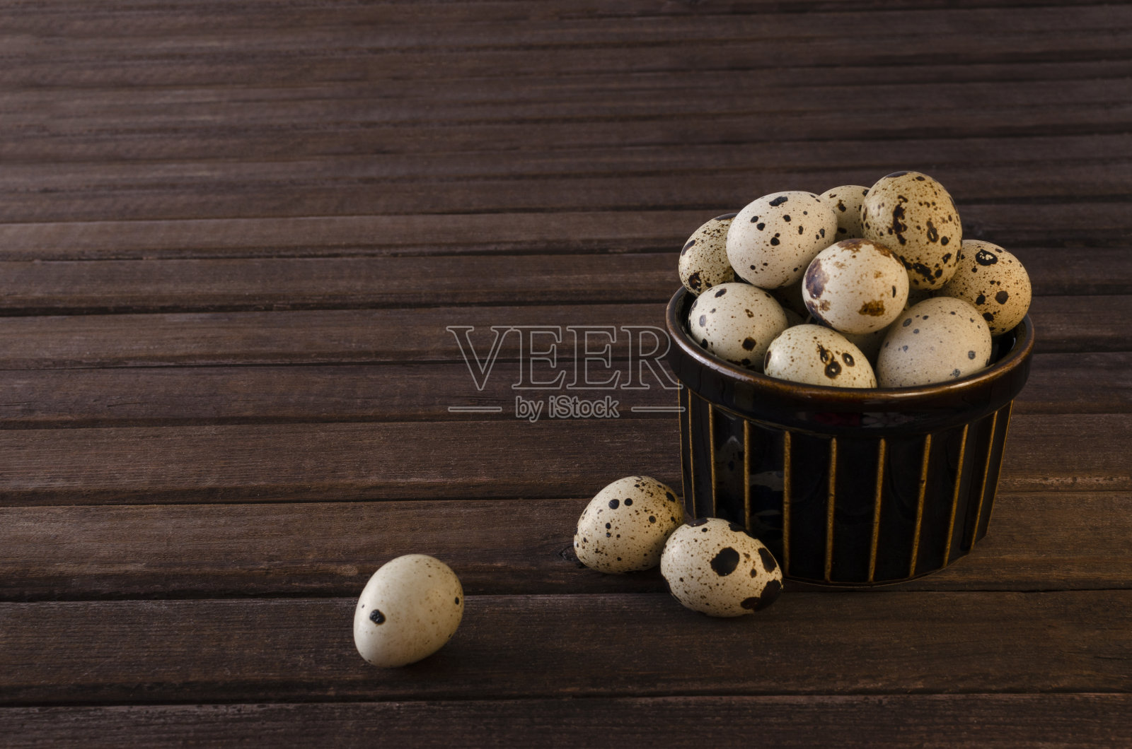 木桌上装满鹌鹑蛋的碗。空的空间照片摄影图片