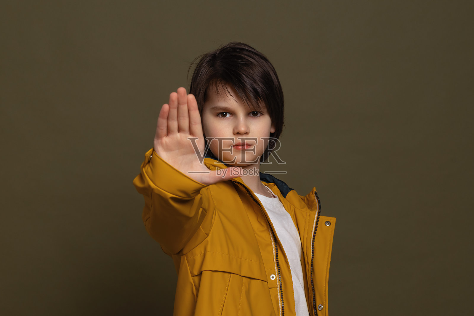 严肃的小男孩穿着休闲服说谢谢但不，伸出手臂在停止标志，拒绝求婚照片摄影图片