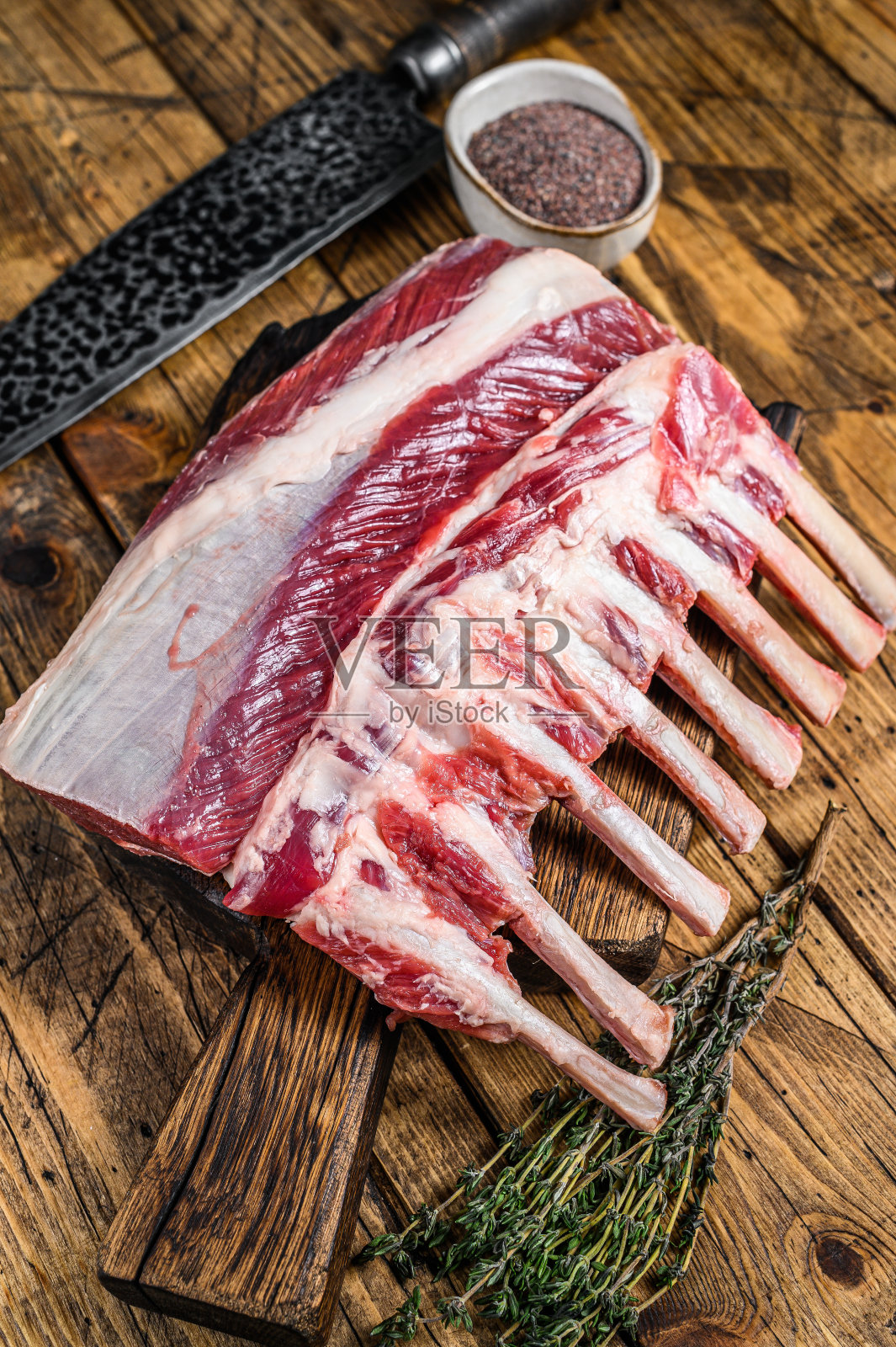 生羊排骨用刀放在砧板上。木制背景。俯视图照片摄影图片
