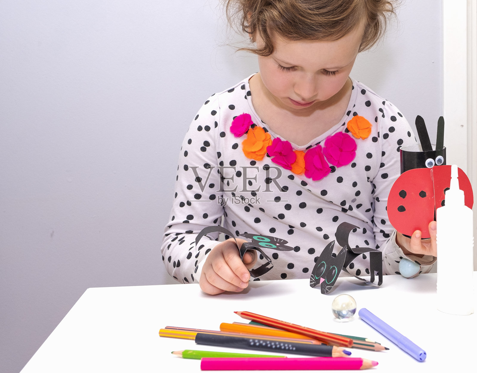 一个5岁的金发白种人女孩在用纸做工艺品。照片摄影图片