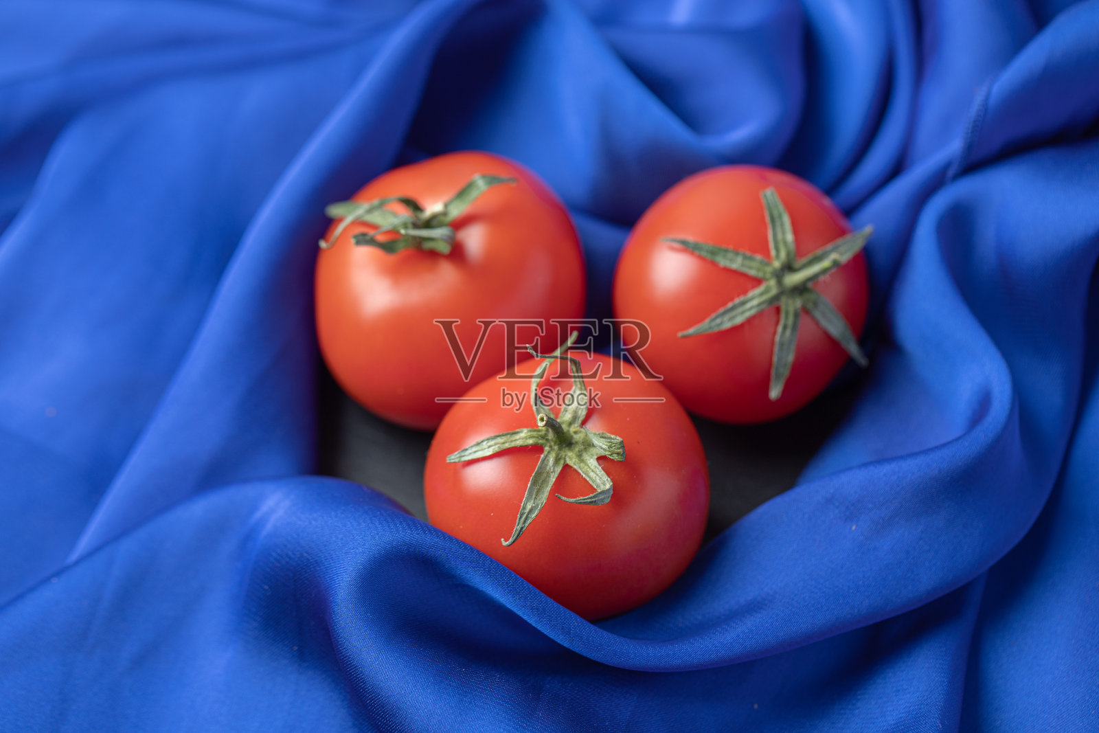 蓝色的桌布上放着新鲜的红番茄照片摄影图片