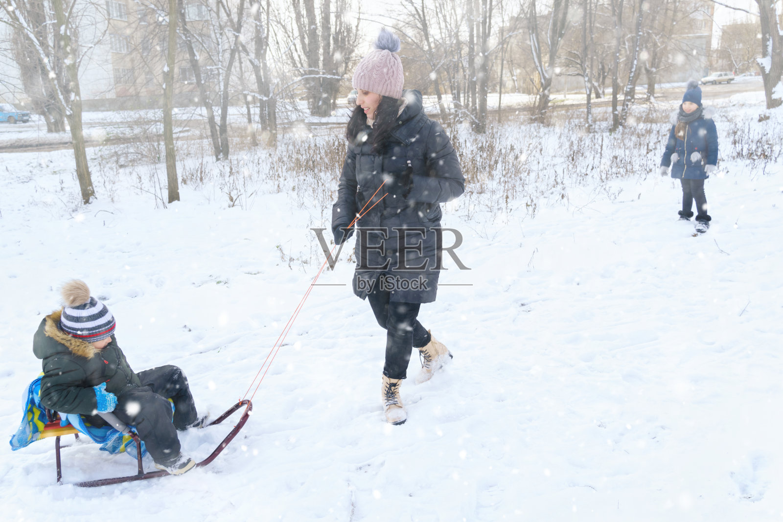 家庭游戏和雪橇在冬天户外，母亲和孩子们在下雪的冬天有乐趣照片摄影图片