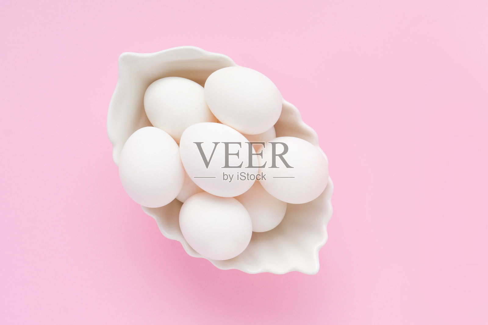 许多白色的鸡蛋在一个白色的盘子在粉红色的背景。复活节。前视图。照片摄影图片