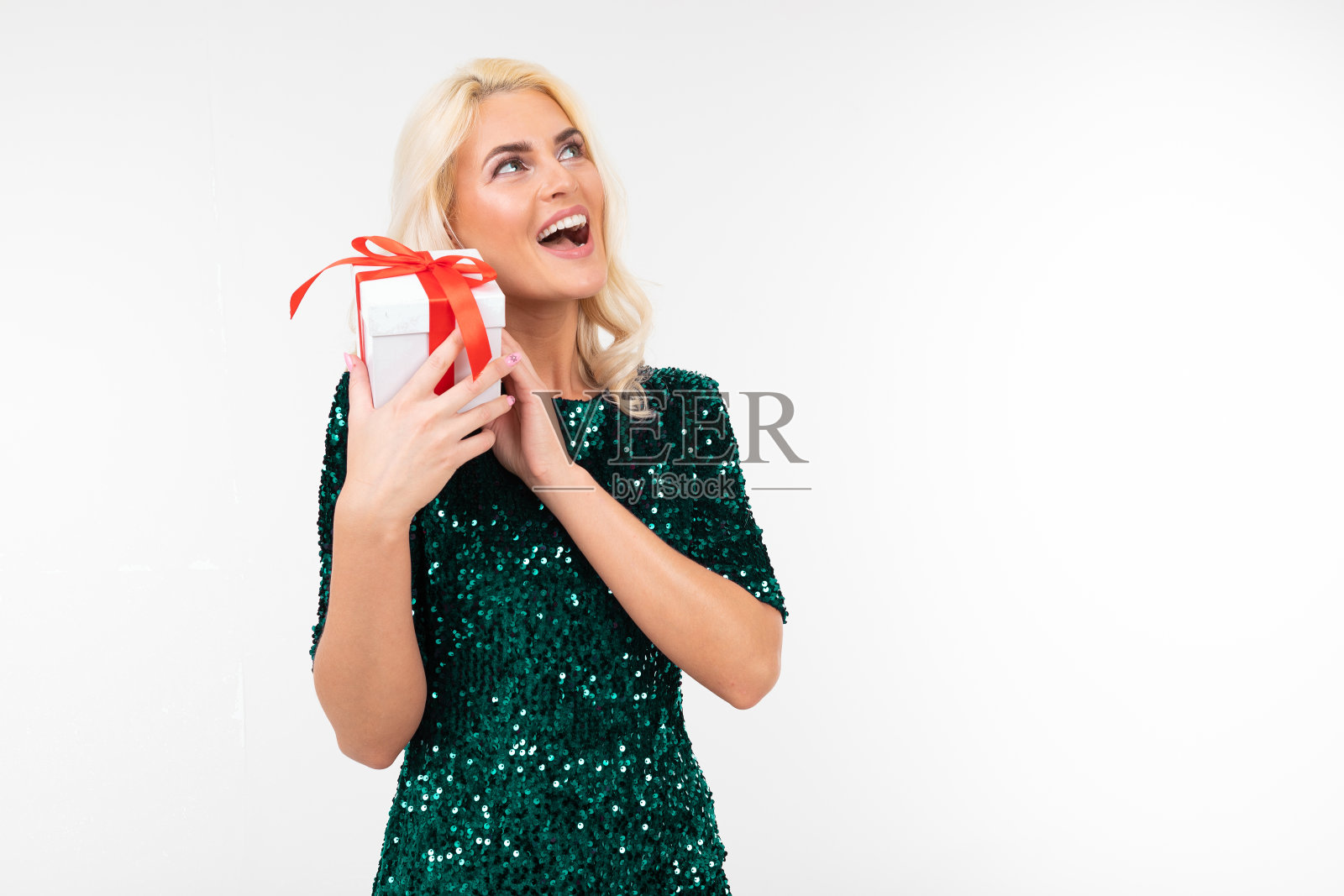 快乐的玩女孩在绿色闪亮的裙子收到一个生日礼物在一个白色的背景与复制空间照片摄影图片