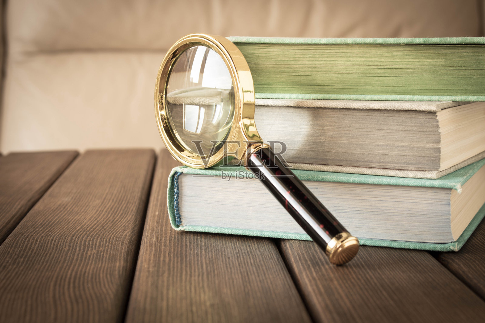 木桌上放着一个放大镜和一堆书。从书本中获取知识的概念。有选择性的重点。照片摄影图片