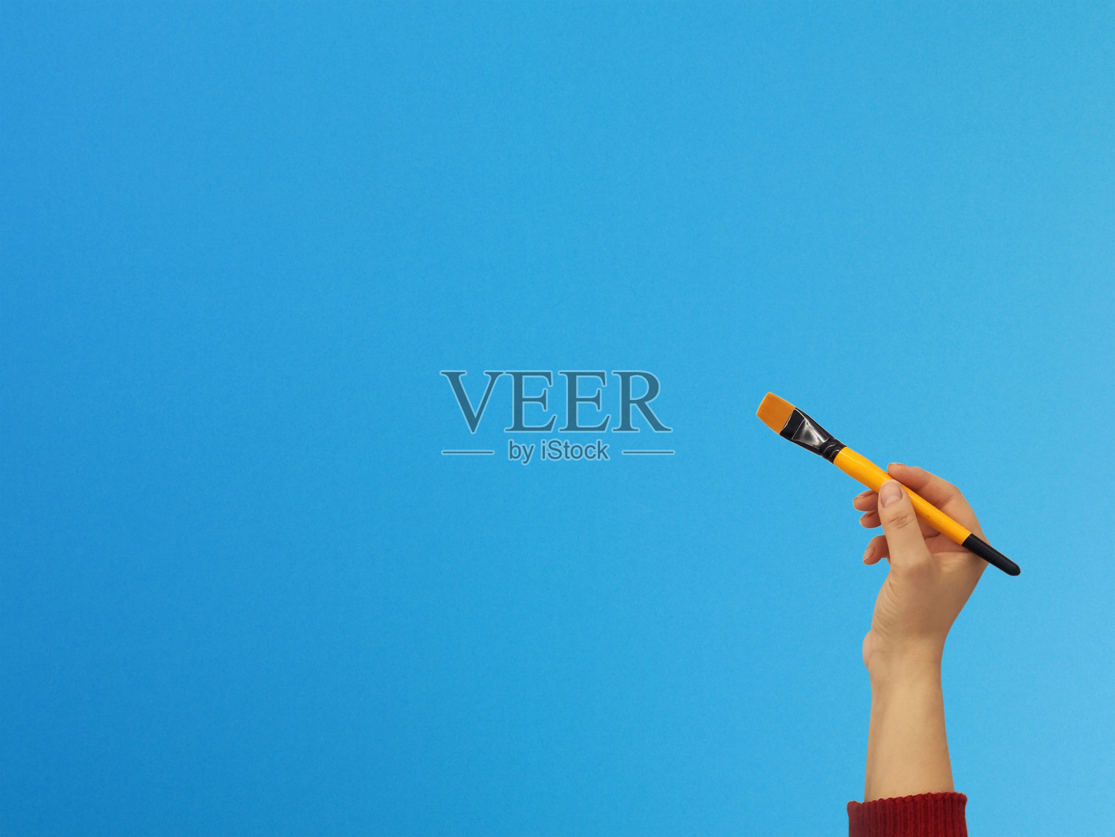 手持画笔与复制空间上的蓝色背景照片摄影图片