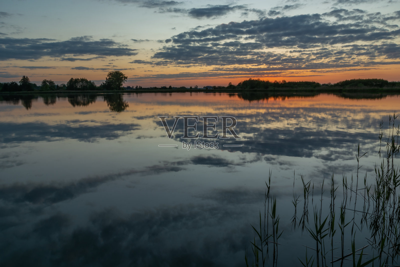 日落后平静的湖面上的云朵倒影照片摄影图片