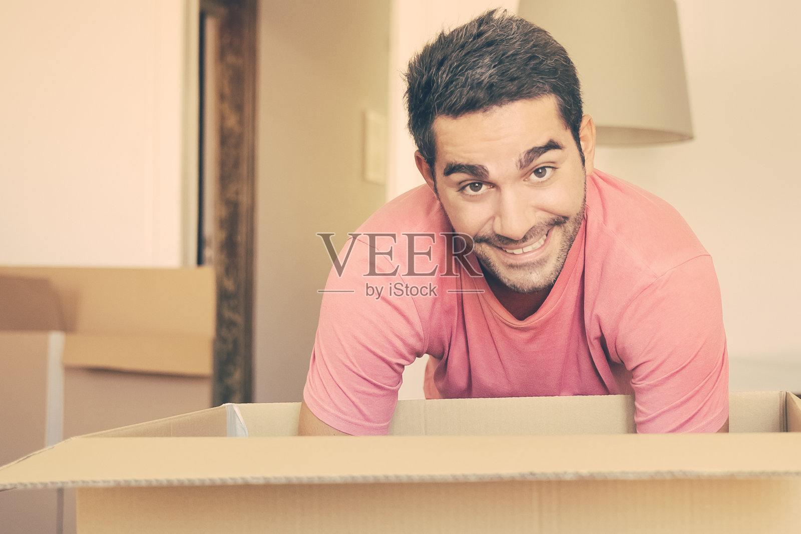 一个兴高采烈的年轻人正在他的新公寓里收拾东西照片摄影图片