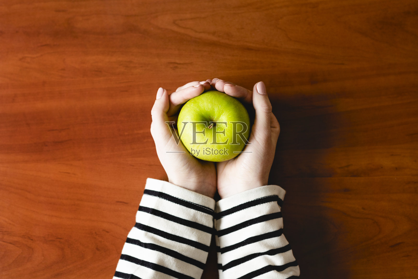 木背景上，一只女性的手举着青苹果。饮食和健康饮食。木背景上的一只女性的手。饮食和健康饮食。照片摄影图片