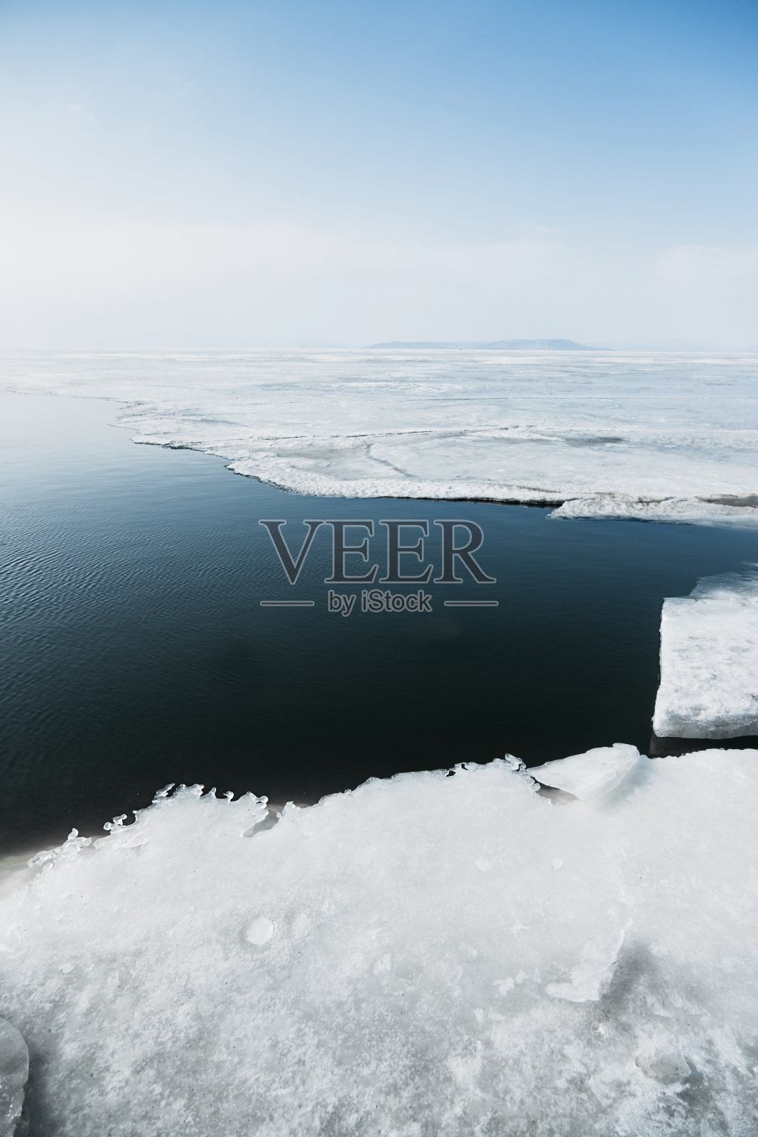 部分融化的海洋被白色的冰和晴朗晴朗的天空包围着。垂直气候内容，选择性聚焦照片摄影图片
