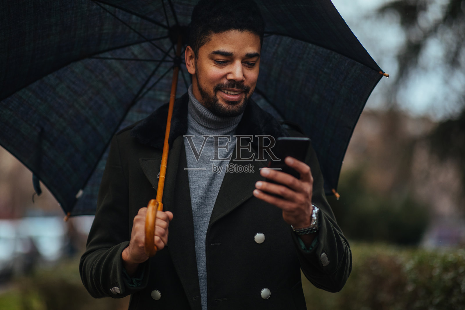 年轻商人在雨伞下使用智能手机照片摄影图片
