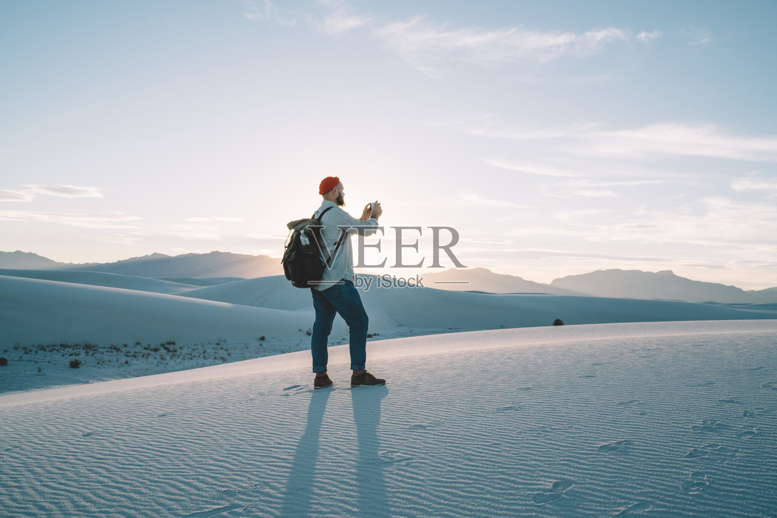 一个无名男子站在沙漠中的小沙山上照片摄影图片
