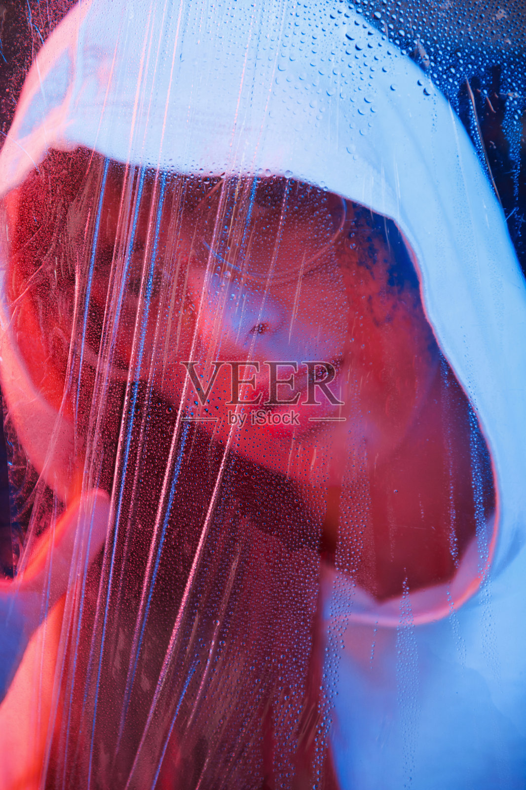 通过玻璃。工作室拍摄在黑暗的工作室与霓虹灯。年轻女孩的肖像照片摄影图片