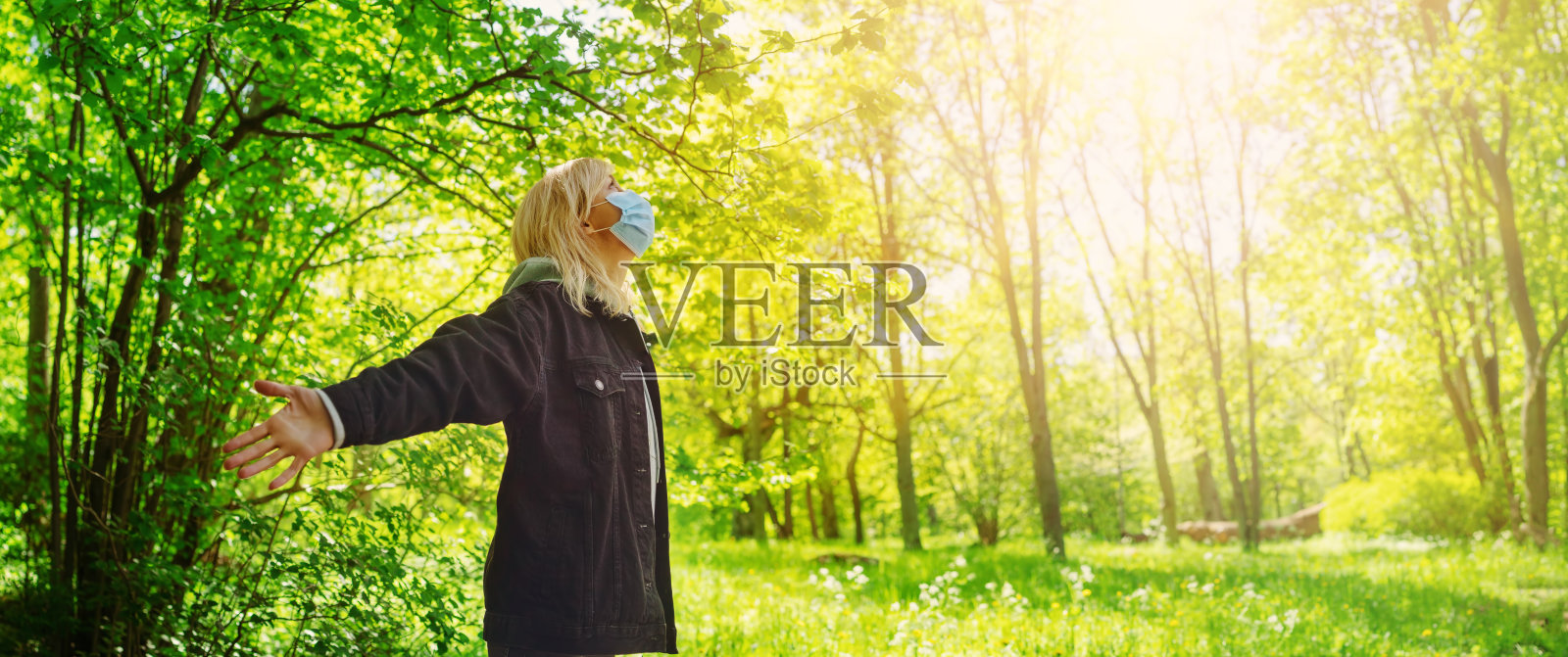 年轻女子戴着医用防护口罩在户外大自然中。照片摄影图片