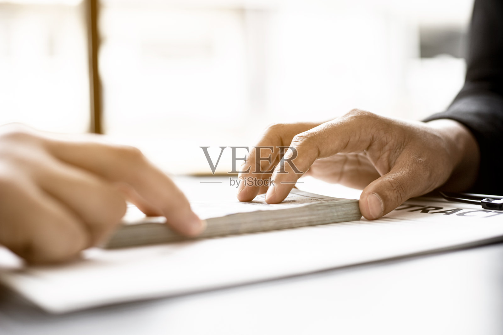 商人们把大笔钞票交给他们的商业伙伴作为贿赂的钱，以欺骗公司，腐败是非法和不道德的。腐败的概念。照片摄影图片