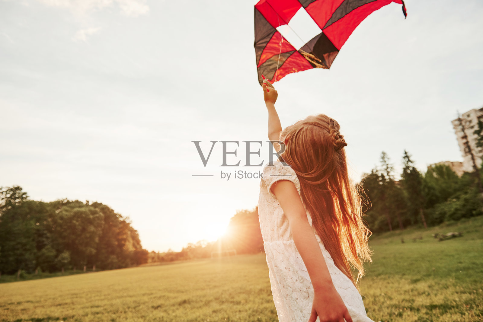 附近的城市。穿着白色衣服的快乐女孩在田野里玩风筝。美丽的大自然照片摄影图片