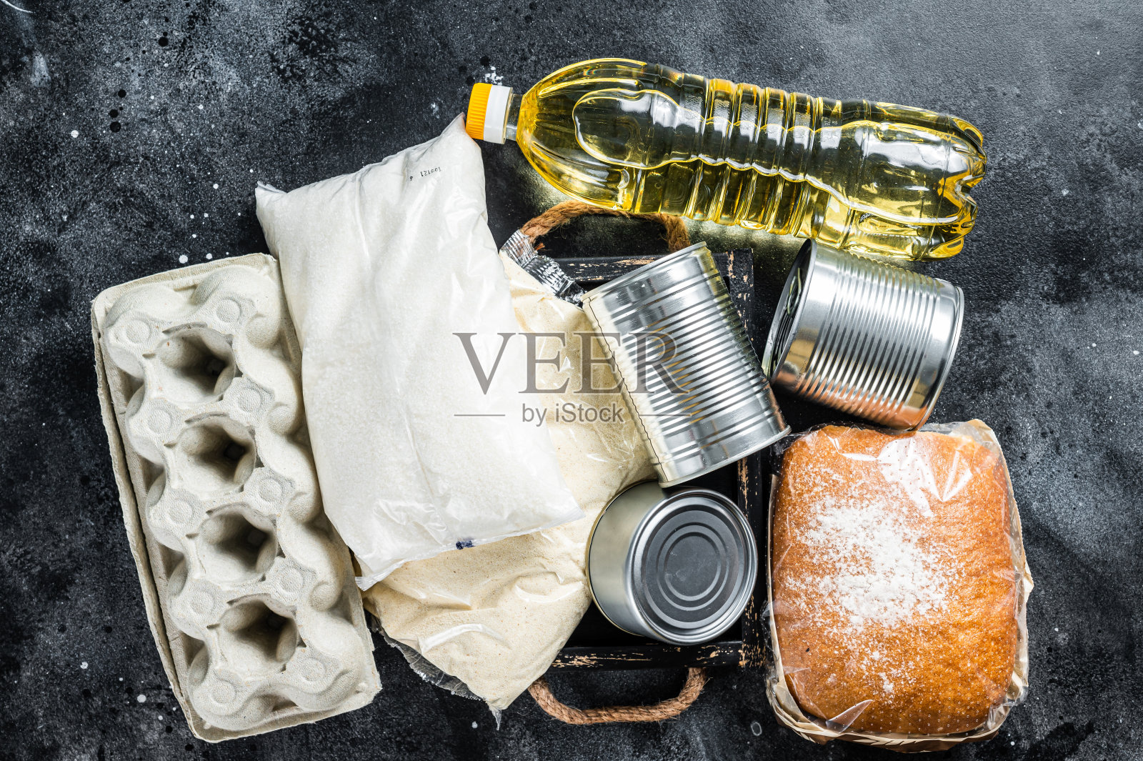 厨房餐桌上有捐赠食品、检疫帮助的理念。油，罐头食品，意大利面，面包，糖，鸡蛋。黑色背景。俯视图照片摄影图片