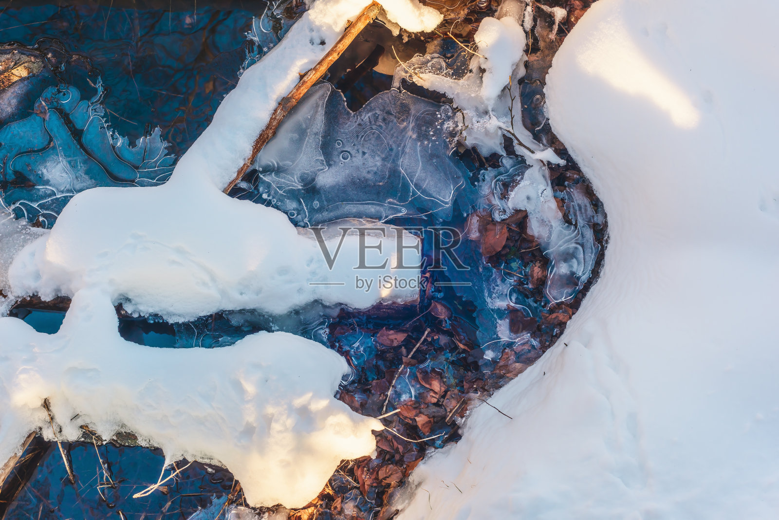 被雪覆盖的浮木躺在冰冻的河里。照片摄影图片