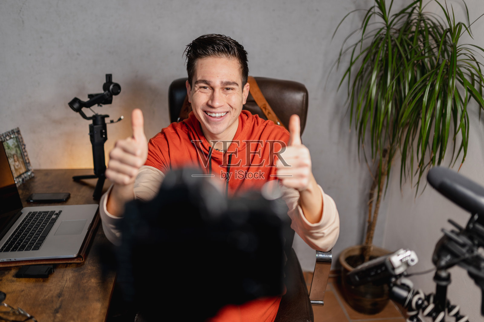 年轻人坐在桌子前对着镜头说话。那家伙在用专业设备录像。视频博客，自由斗士的概念。照片摄影图片