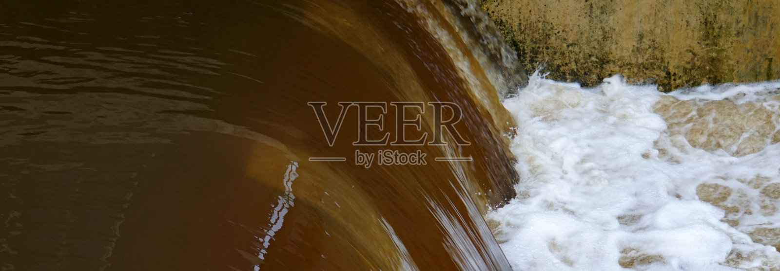 铁锈色的水溢出大坝。照片摄影图片