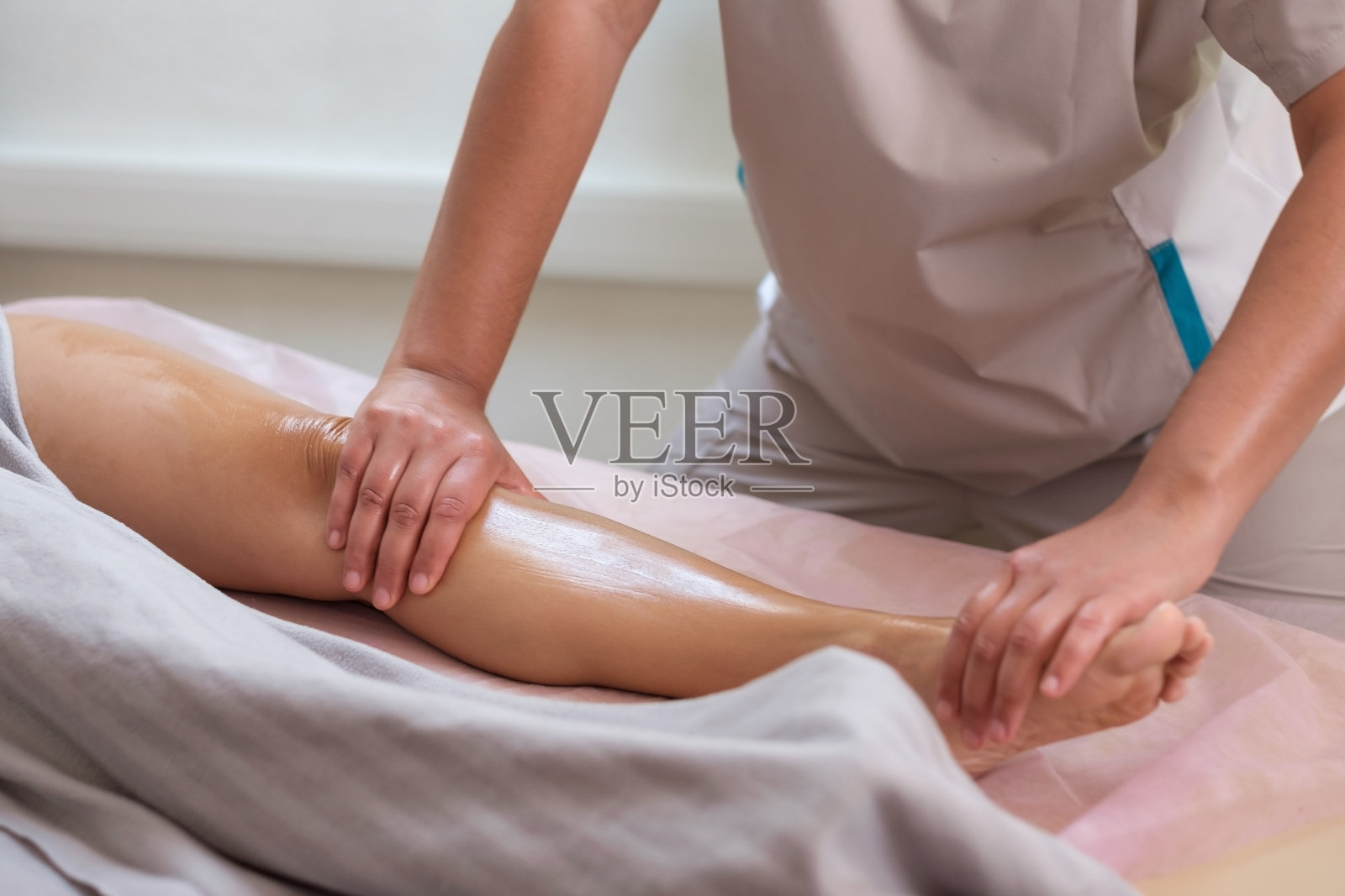 白种妇女接受水疗治疗腿部按摩。医疗保健的概念。照片摄影图片