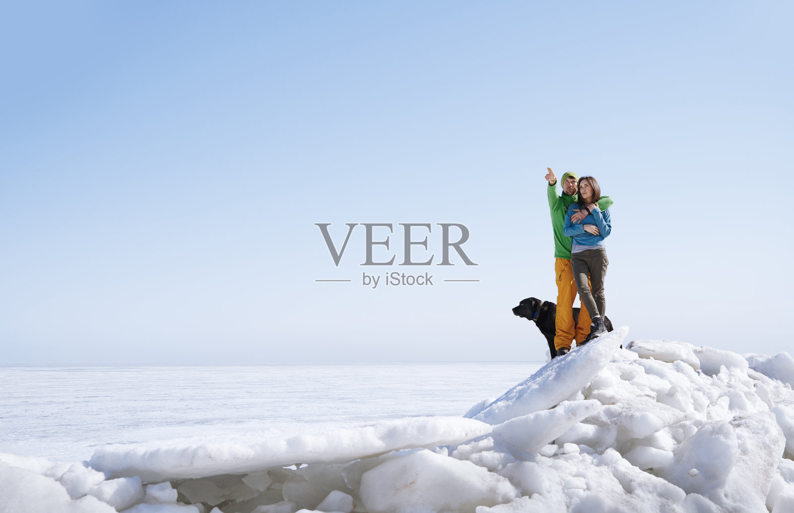 年轻的成年夫妇和狗在户外探索冬天的风景照片摄影图片