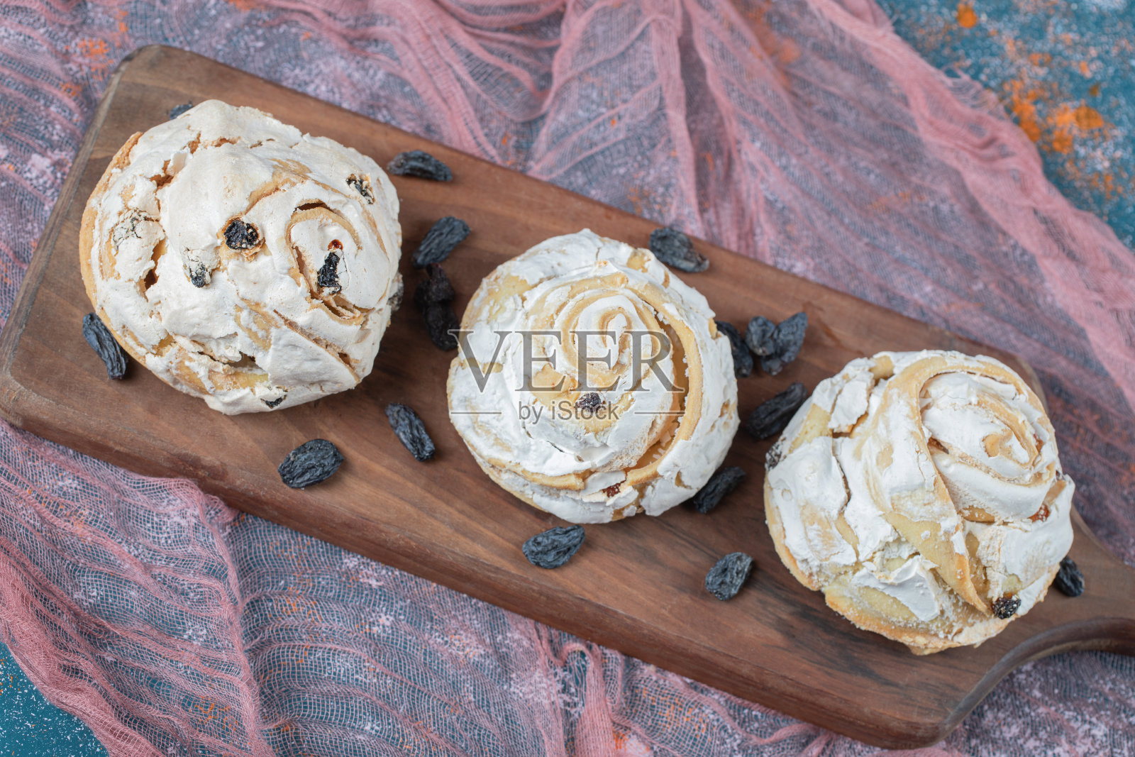 白色的蛋白酥饼和黑色的葡萄干放在木板上照片摄影图片