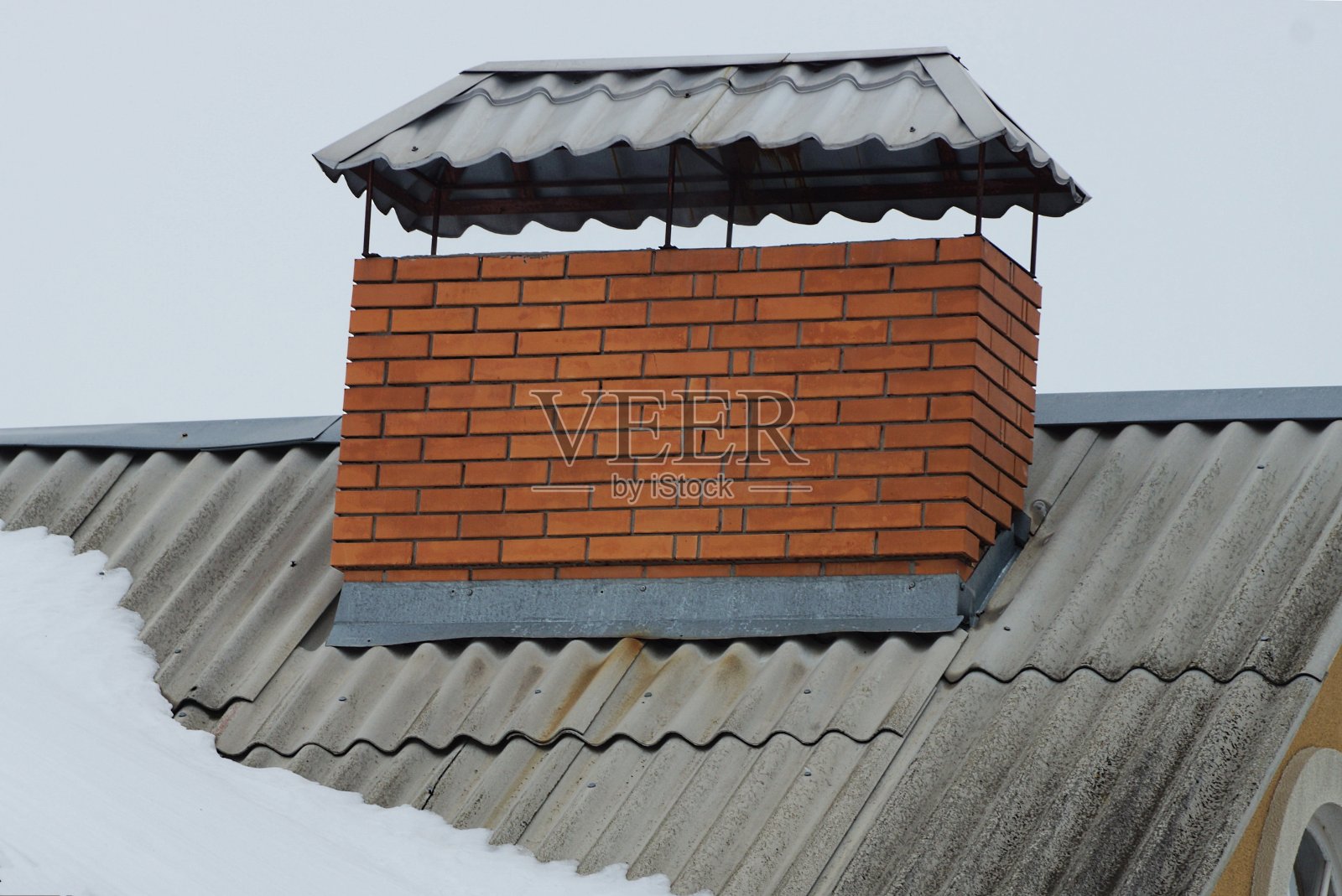 灰色石板屋顶上有一个棕色砖砌的大烟囱照片摄影图片