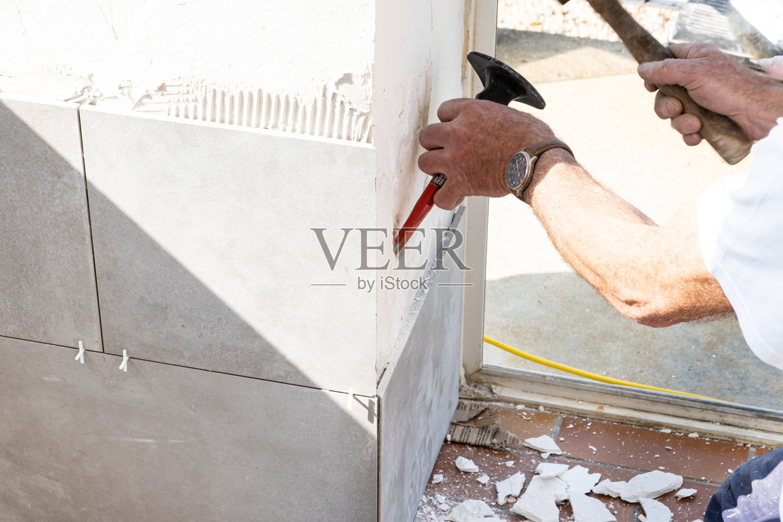 泥瓦匠在铺瓷砖之前先用凿子把墙凿好照片摄影图片